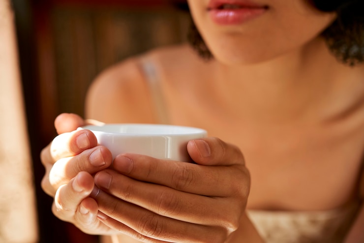 Foto nahaufnahme einer jungen frau, die eine tasse warmen, köstlichen kräutertee hält