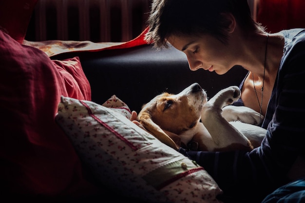 Nahaufnahme einer jungen Frau, die mit einem Hund auf dem Bett spielt