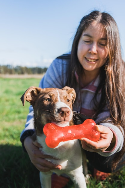 Nahaufnahme einer jungen Frau, die mit ihrem Welpen spielt und den Moment mit einem Hundeknochenspielzeug genießt.