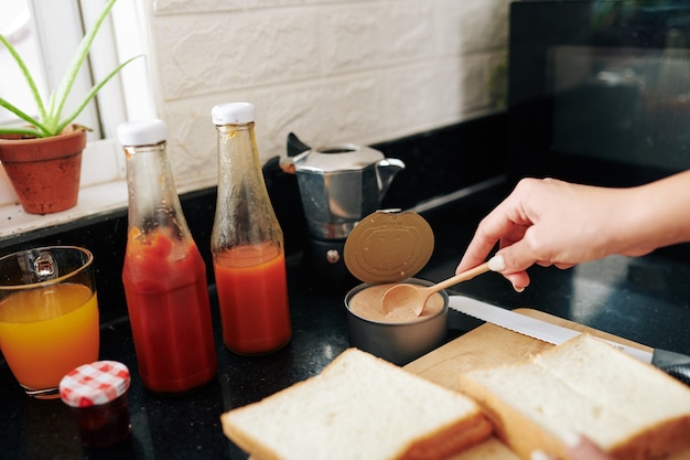 Foto nahaufnahme einer jungen frau, die sandwiches mit putenpastete und ketchup zum frühstück macht