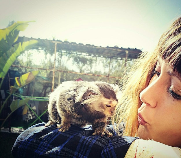 Foto nahaufnahme einer jungen frau mit einem gewöhnlichen marmoset gegen den himmel