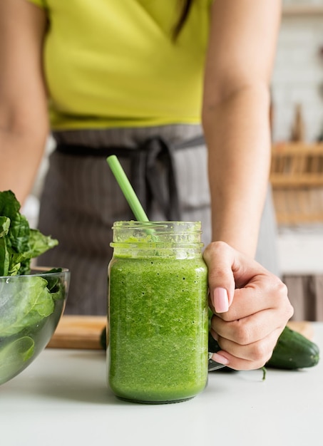 Nahaufnahme einer jungen Frau mit einem Glas grünen Smoothie