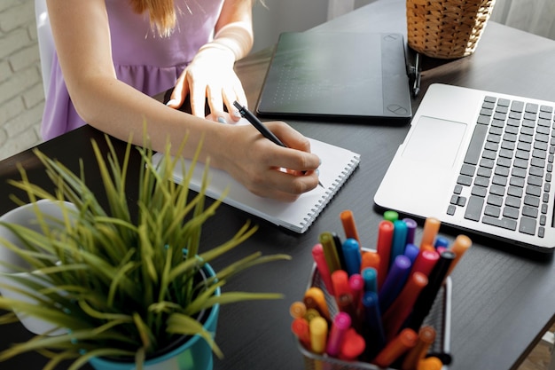 Nahaufnahme einer jungen Geschäftsfrau, die im modernen Büro arbeitet und sich Notizen macht