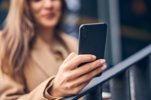 Nahaufnahme einer jungen kaukasischen Frau, die ein Mobiltelefon vor sich hält