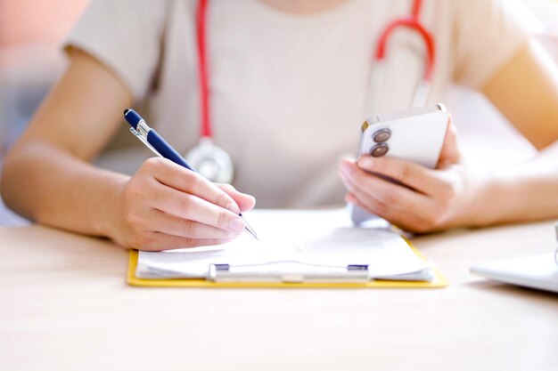 Foto nahaufnahme einer jungen medizinstudentin in freizeitkleidung, die arbeitet und eine kurze notiz mit dem smartphone macht