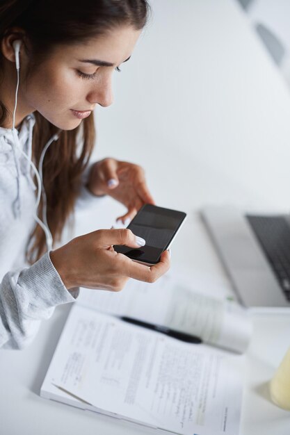 Nahaufnahme einer jungen perfekten Frau, die mit einem Smartphone Teile des Buches erfasst, um sie bei zukünftigen Prüfungen als Spickzettel zu verwenden Bildungskonzept