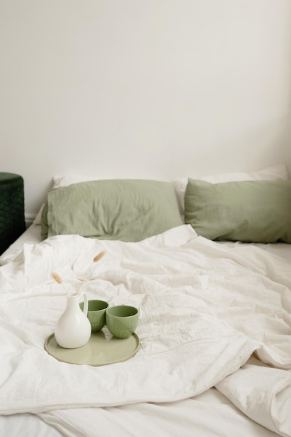 Nahaufnahme einer Kaffeetasse auf dem Bett mit grünen Kissen