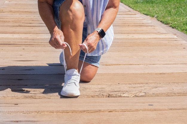 Nahaufnahme einer kaukasischen Frau, die Schnürsenkel bindet Weiblicher Sport-Fitness-Läufer, der sich an einem sonnigen Tag zum Joggen im Freien fertig macht