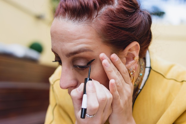 Nahaufnahme einer kaukasischen jungen Frau, die schwarzen Eyeliner auf ihrem Gesicht berührt