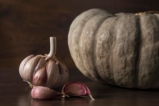 Nahaufnahme einer Knoblauchknolle und im Hintergrund eine Kürbisbeschwörung von Halloween