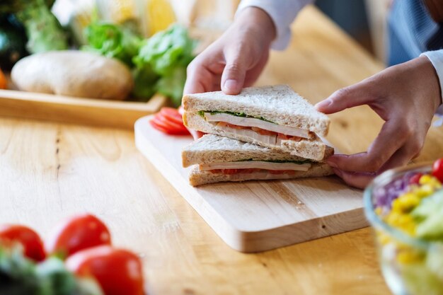 Nahaufnahme einer Köchin, die ein Stück Vollkornsandwich in der Küche kocht und hält