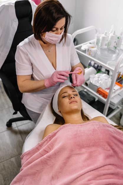 Nahaufnahme einer Kosmetikerin, die eine chemische Peeling-Behandlung bei einem Patienten in einem Schönheits-Spa anwendet, um Hautverjüngung, Teint und Akne-Schönheitsbehandlungen zu erzielen
