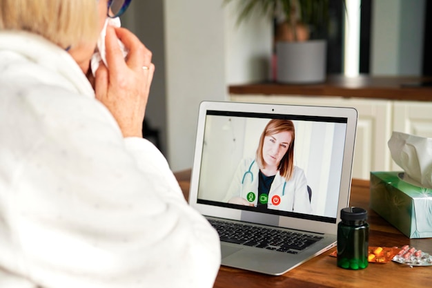 Nahaufnahme einer kranken älteren Frau, die einen Videoanruf mit einem Arzt hat