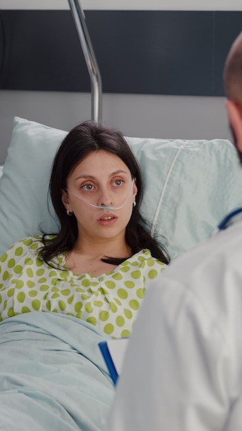 Nahaufnahme einer kranken Frau mit nasalem Sauerstoffschlauch, die im Bett ruht