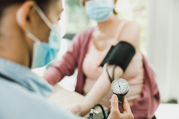 Nahaufnahme einer Krankenschwester, die den Blutdruck einer älteren Frau überprüft.