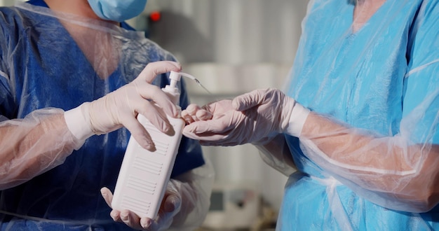 Nahaufnahme einer Krankenschwester, die eine Flasche mit antiseptischem Gel für den Chirurgen hält