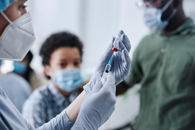 Nahaufnahme einer Krankenschwester in Schutzhandschuhen, die während des Eingriffs im Krankenhaus eine Spritze mit Medikamenten füllt