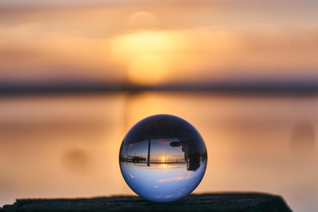 Nahaufnahme einer Kristallkugel auf Wasser gegen Sonnenuntergang.