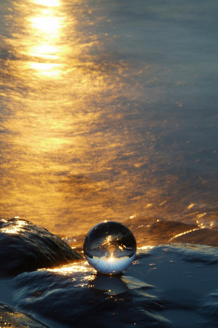 Foto nahaufnahme einer kristallkugel im meer gegen den sonnenuntergang