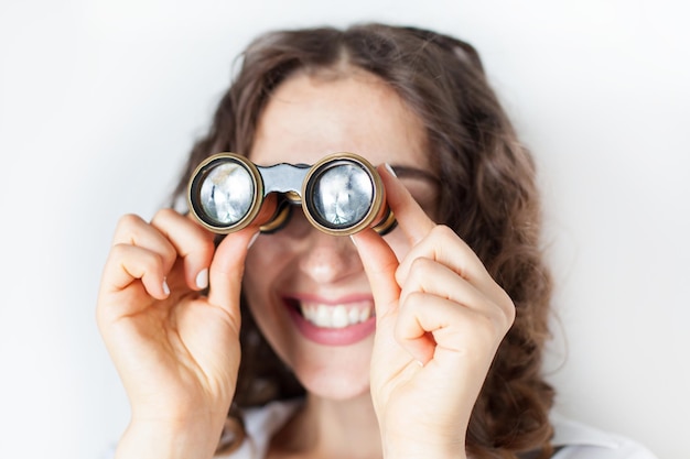 Nahaufnahme einer lächelnden Frau, die durch ein Fernglas an die Wand schaut