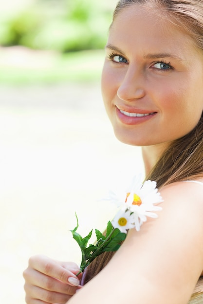 Nahaufnahme einer lächelnden Frau mit einer Blume