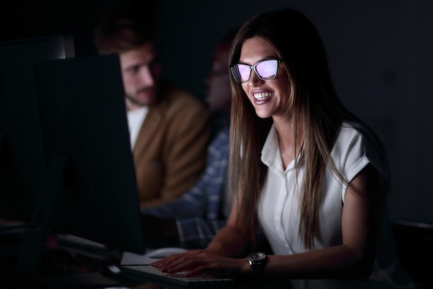 Nahaufnahme einer lächelnden Geschäftsfrau, die an einem Computerfoto auf schwarzem Hintergrund arbeitet