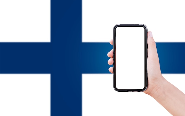 Nahaufnahme einer männlichen Hand, die ein Smartphone mit Leerzeichen auf dem Bildschirm auf dem Hintergrund der unscharfen Flagge Finnlands hält