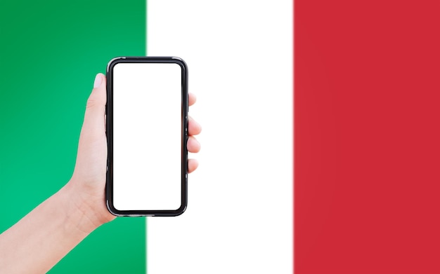 Nahaufnahme einer männlichen Hand, die ein Smartphone mit Leerzeichen auf dem Bildschirm auf dem Hintergrund der unscharfen Flagge Italiens hält