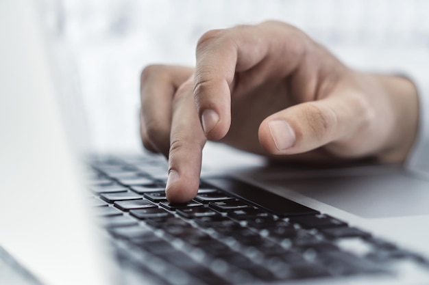 Nahaufnahme einer männlichen Hand drückt eine Taste auf der Laptop-Tastatur