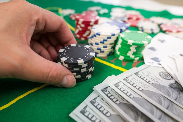 Nahaufnahme einer menschlichen Hand mit Peoker-Chips auf einem grünen Casino-Tisch Gamble Poker-Konzept