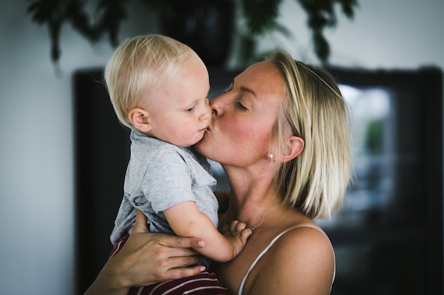 Nahaufnahme einer Mutter, die ihren Jungen zu Hause küsst