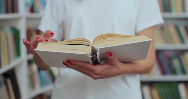 Nahaufnahme einer nicht erkennbaren Studentin, die ein Buch liest, das in der Universitätsbibliothek nach Informationen sucht Selbstbildungskonzept