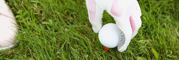 Nahaufnahme einer Person, die den weißen und rosafarbenen Schutzhandschuh des Golfballs auf der Spielerausrüstung aufhebt