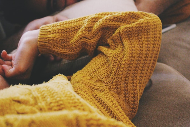 Nahaufnahme einer Person, die einen Pullover trägt und auf dem Sofa liegt