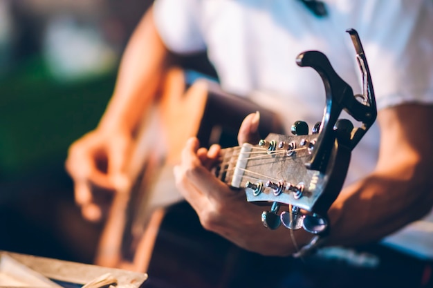 Foto nahaufnahme einer person, die gitarre mit unscharfem hintergrund spielt