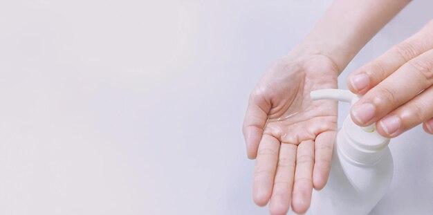 Nahaufnahme einer Person, die Handdesinfektionsmittel auf weißem Hintergrund verwendet