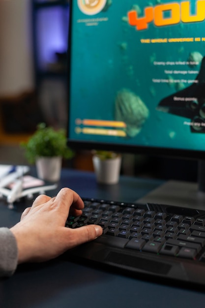 Nahaufnahme einer Person, die Tastatur verwendet und Videospiele auf dem Computer spielt. Spieler, die Online-Spiele auf einem Monitor mit Tastatur spielen und moderne Spielgeräte haben. Spieler, der Kontroll-Gadget verwendet.