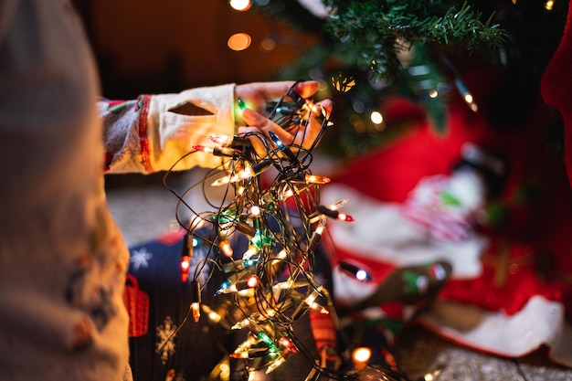 Nahaufnahme einer Person im gemütlichen Schlafanzug mit beleuchteten Weihnachtslichtern