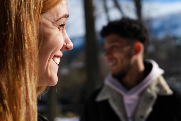 Foto nahaufnahme einer profilansicht des gesichts einer lächelnden frau im vordergrund und des gesichts eines unfokussierten lächelnden bartmannes im profil im hintergrund, natürlicher horizontaler hintergrund