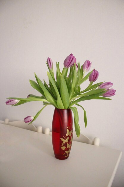 Nahaufnahme einer rosa Blumenvase auf dem Tisch gegen die Wand