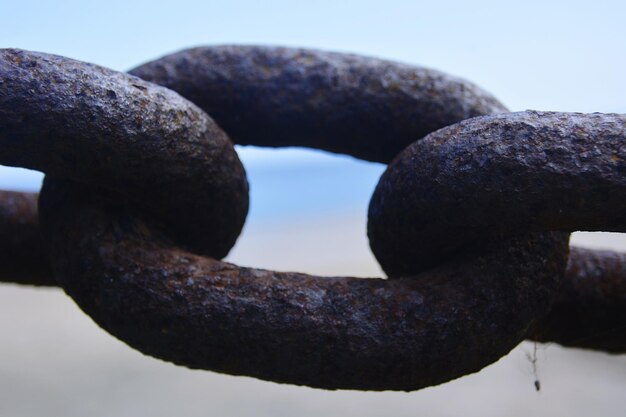 Foto nahaufnahme einer rostigen kette vor klarem himmel