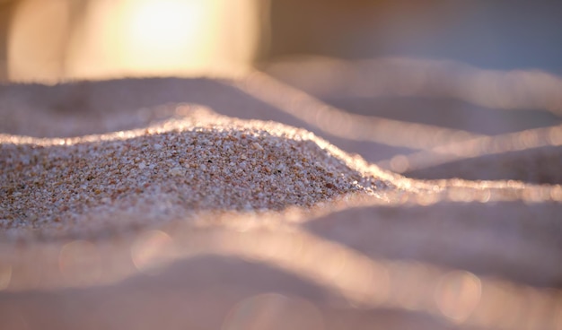 Nahaufnahme einer sauberen gelben Sandfläche, die den mit Abendlicht beleuchteten Strand am Meer bedeckt Reise- und Urlaubskonzept