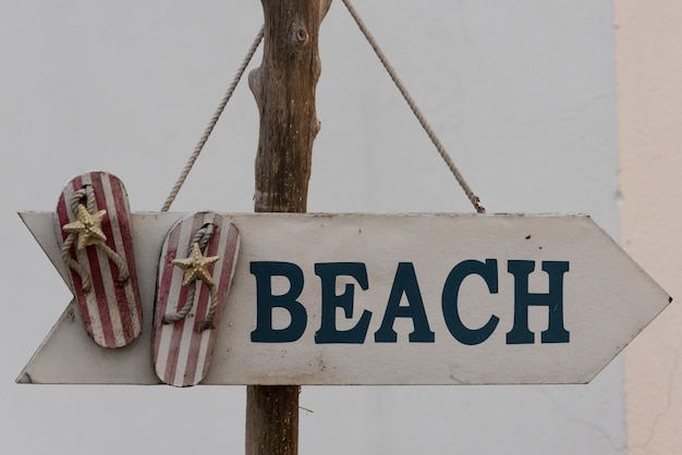 Nahaufnahme einer Schildtafel, die an einem Holzpfahl am Strand hängt