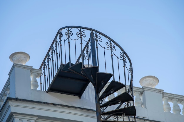 Nahaufnahme einer schönen schmiedeeisernen Außenwendeltreppe an der Seite eines Hauses