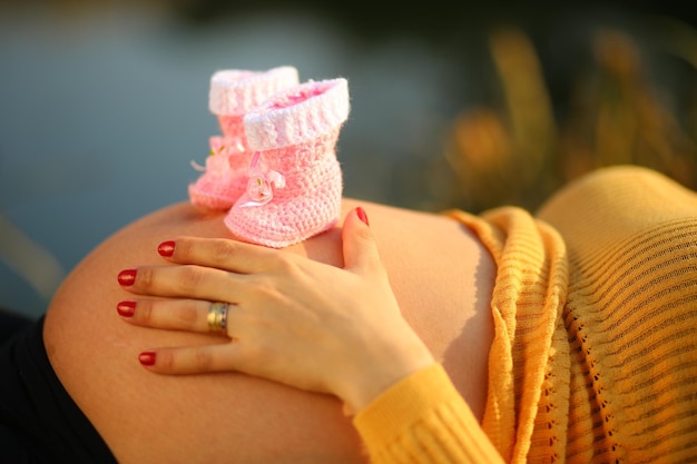 Nahaufnahme einer schwangeren Frau mit Baby-Stiefeln auf dem Bauch