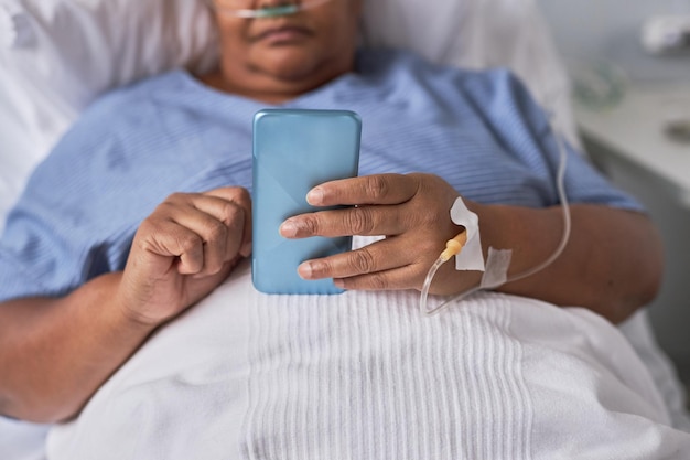 Nahaufnahme einer schwarzen Frau mit Smartphone im Krankenhaus