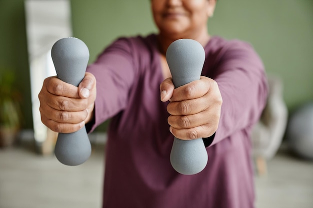 Nahaufnahme einer schwarzen Seniorin, die Hanteln hält und zu Hause trainiert, Kopierraum