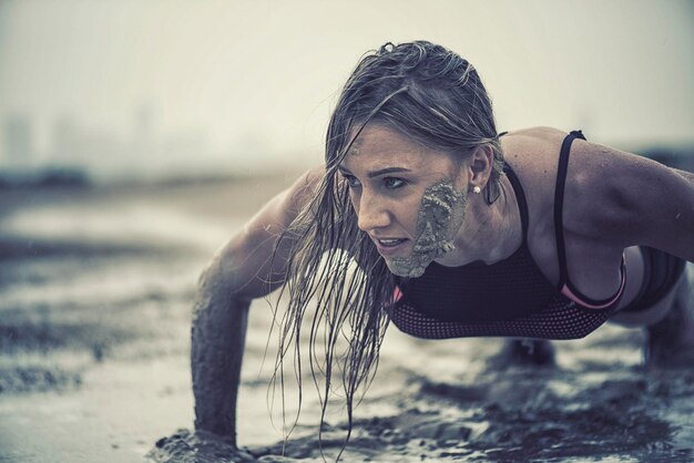 Foto nahaufnahme einer sportlichen frau, die im schlamm trainiert