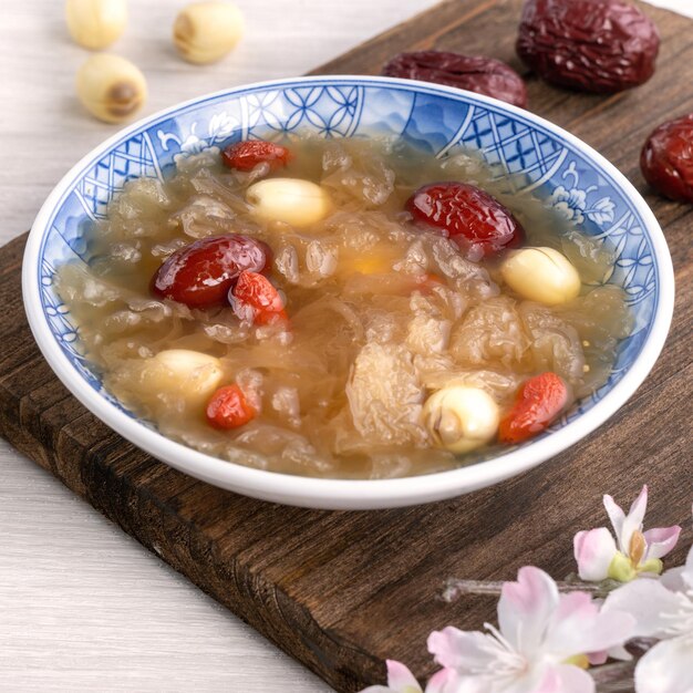 Nahaufnahme einer traditionellen chinesischen süßen schneeweißen Pilzsuppe mit Lotus-Samen, roten Datteln, Jujube und Wolfberry Goji-Beere Gojiberry auf weißem Hintergrund