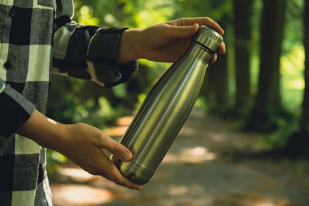 Foto nahaufnahme einer unerkennbaren weiblichen hand, die eine wasserflasche in einer wiederverwendbaren stahl-thermo-wasserflasche hält